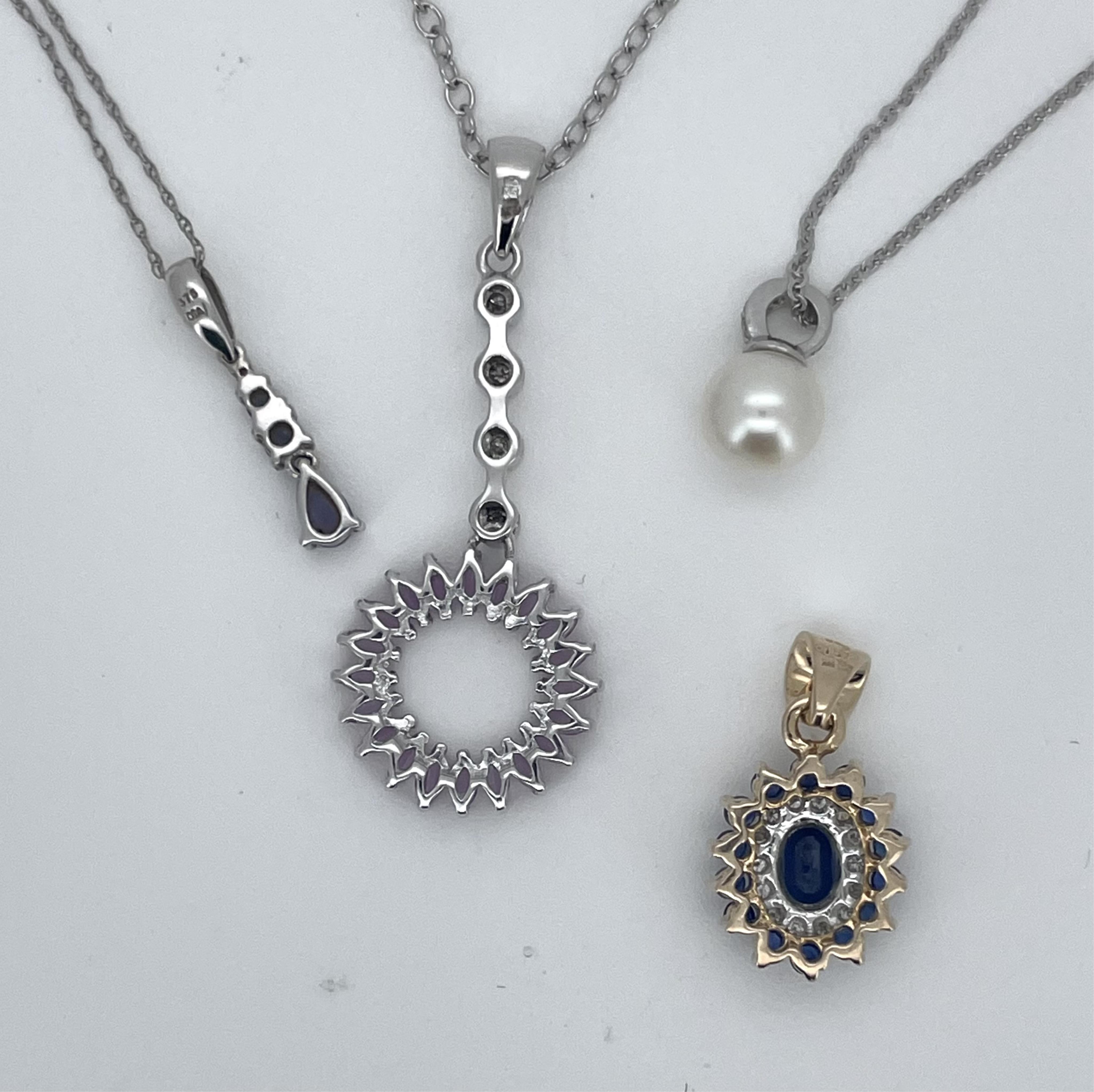 A modern 9ct gold, sapphire and diamond set oval cluster pendant, overall 20mm, together with three assorted 9ct white gold or 375 and gem set pendants including cultured pearl, with 375 white metal chains, gross weight